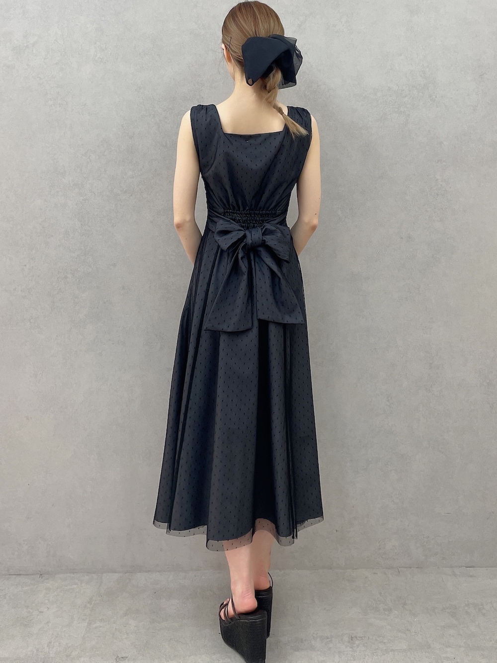 ブラック系のサンダル、ブラック系のワンピース、ブラック系のハンドバッグを着用したレディースの春コーディネートの4枚目の写真