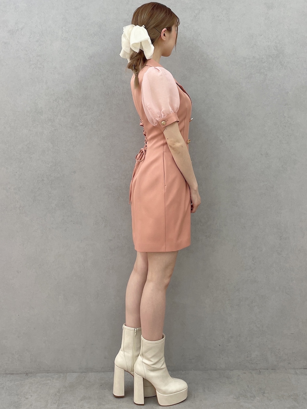 オレンジ系のワンピース、ホワイト系のブーツ、ホワイト系のバレッタ/ヘアクリップを着用したレディースの春コーディネートの3枚目の写真