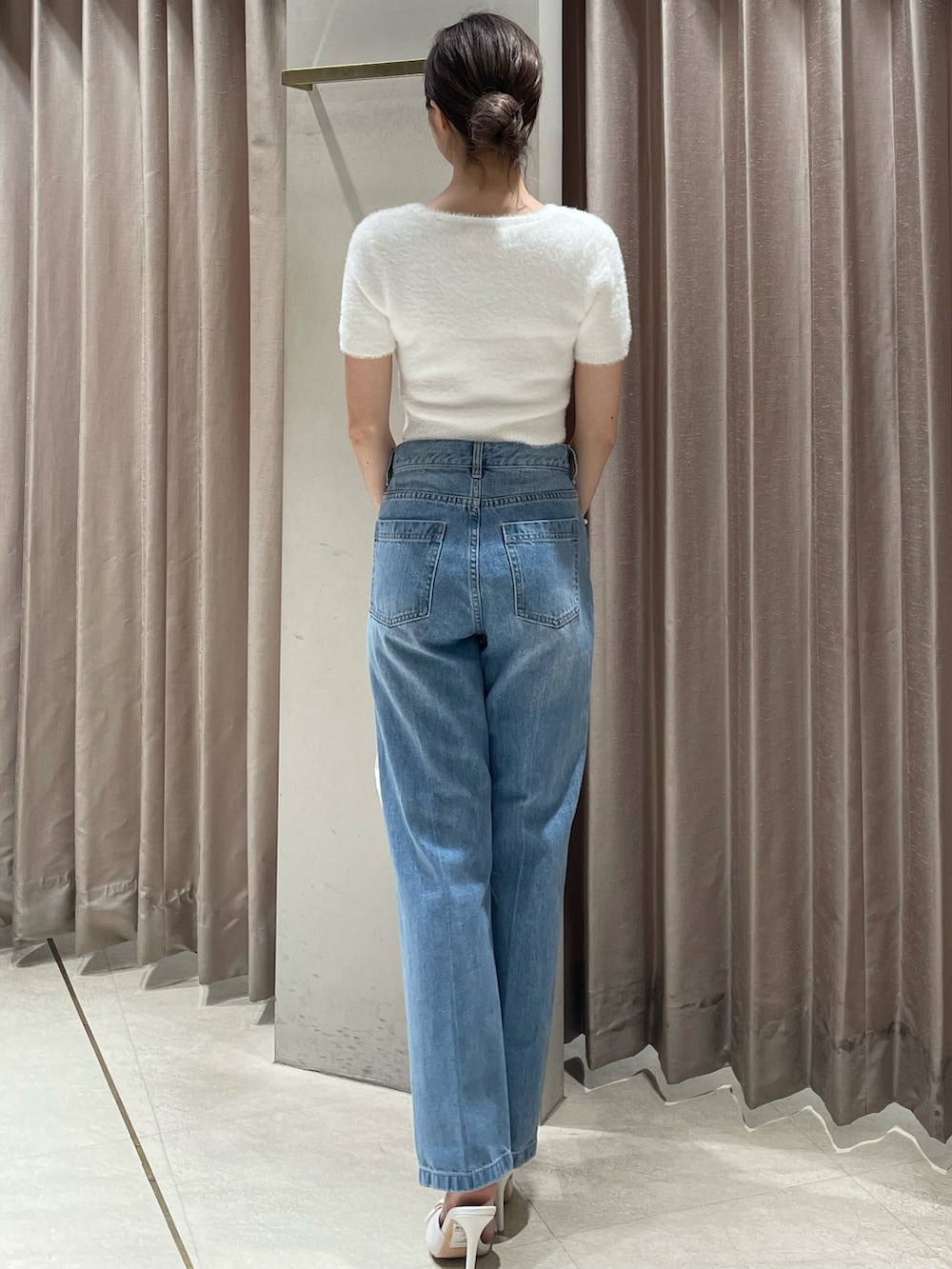 ホワイト系のハンドバッグ、ホワイト系のニット/セーター、ブルー系のデニムパンツを着用したレディースの夏コーディネートの3枚目の写真