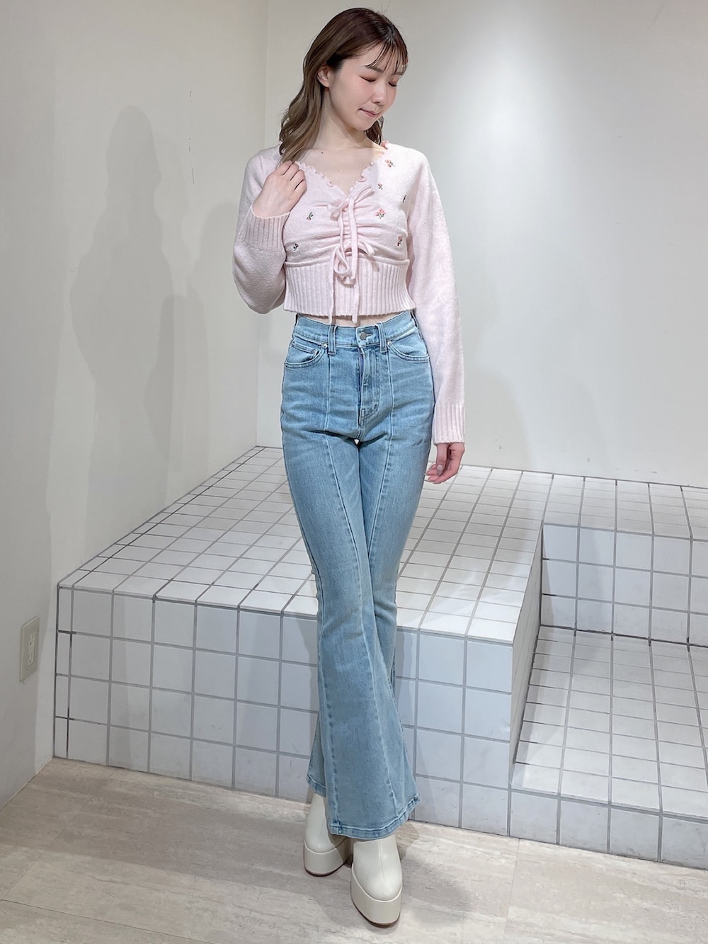 ピンク系のニット/セーター、ブルー系のデニムパンツ、ホワイト系のブーツを着用したレディースの冬コーディネートの2枚目の写真