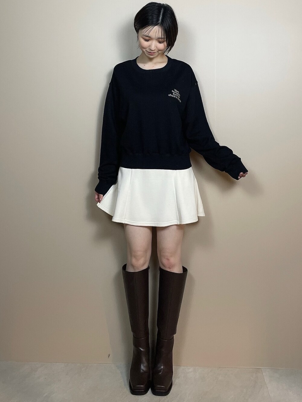 ホワイト系のスカート、ブラウン系のブーツ、ブラック系のスウェットを着用したレディースの夏コーディネートの2枚目の写真