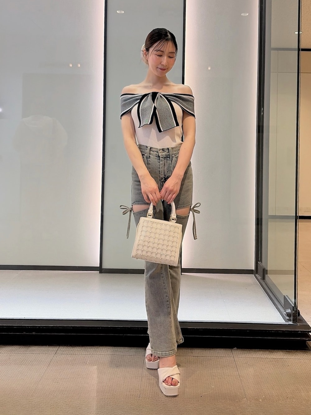 ホワイト系のニット/セーター、ブルー系のデニムパンツ、ホワイト系のハンドバッグを着用したレディースの夏コーディネートの2枚目の写真