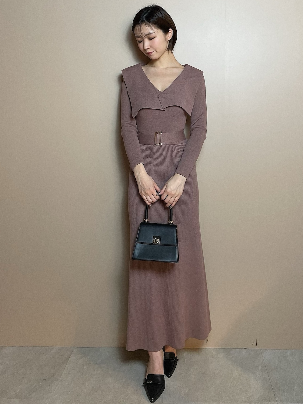 ピンク系のワンピース、ブラック系のハンドバッグ、ブラック系のパンプスを着用したレディースの冬コーディネートの2枚目の写真