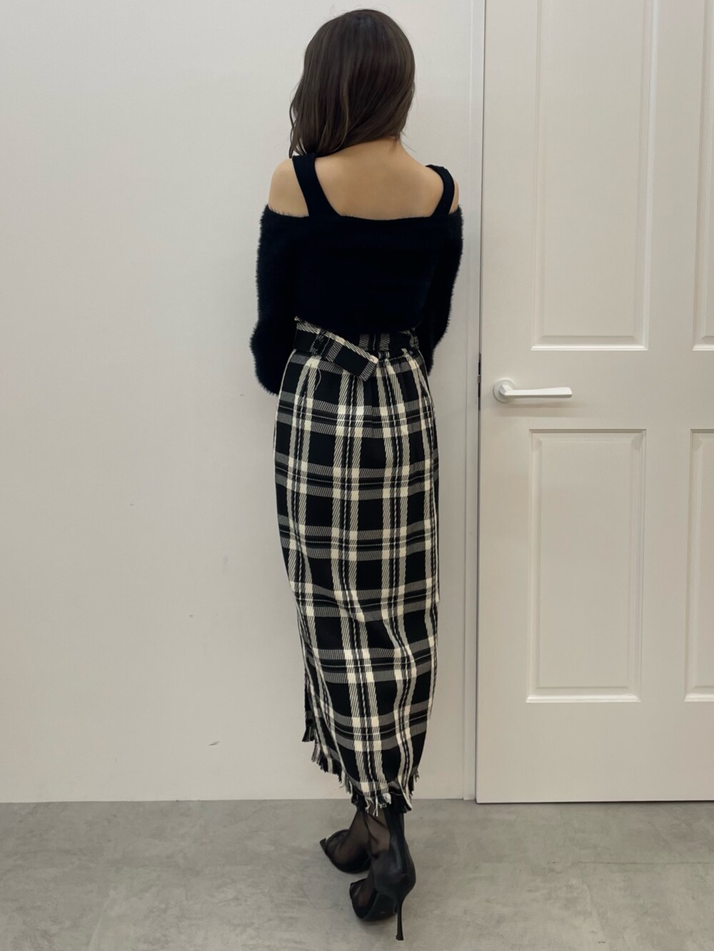 ブラック系のニット/セーター、ブラック系のスカート、ブラック系のハンドバッグを着用したレディースの夏コーディネートの4枚目の写真