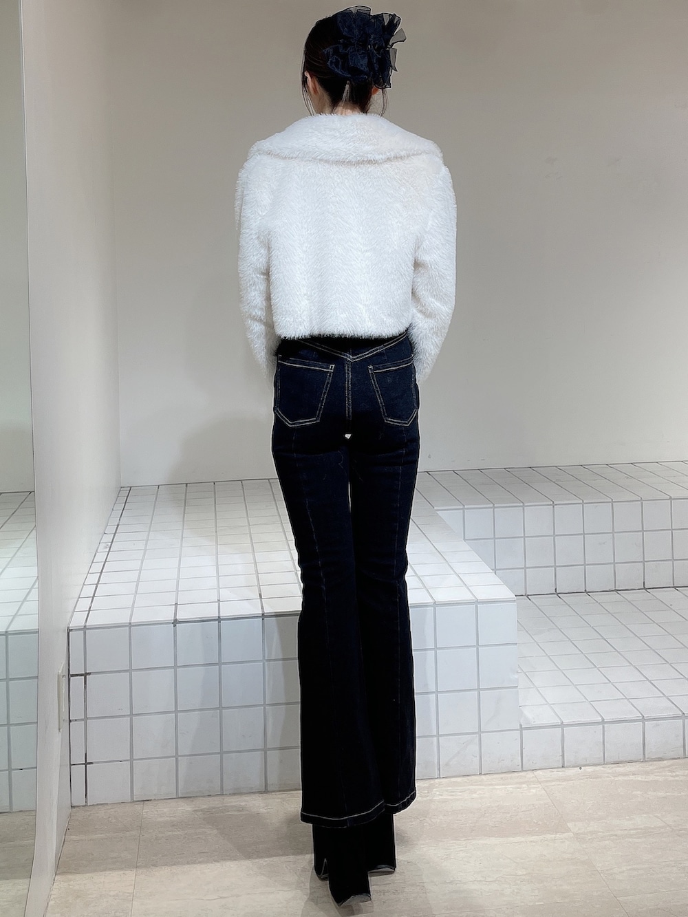 ホワイト系のブルゾン、ブラック系のニット/セーター、ブラック系のデニムパンツを着用したレディースの冬コーディネートの4枚目の写真