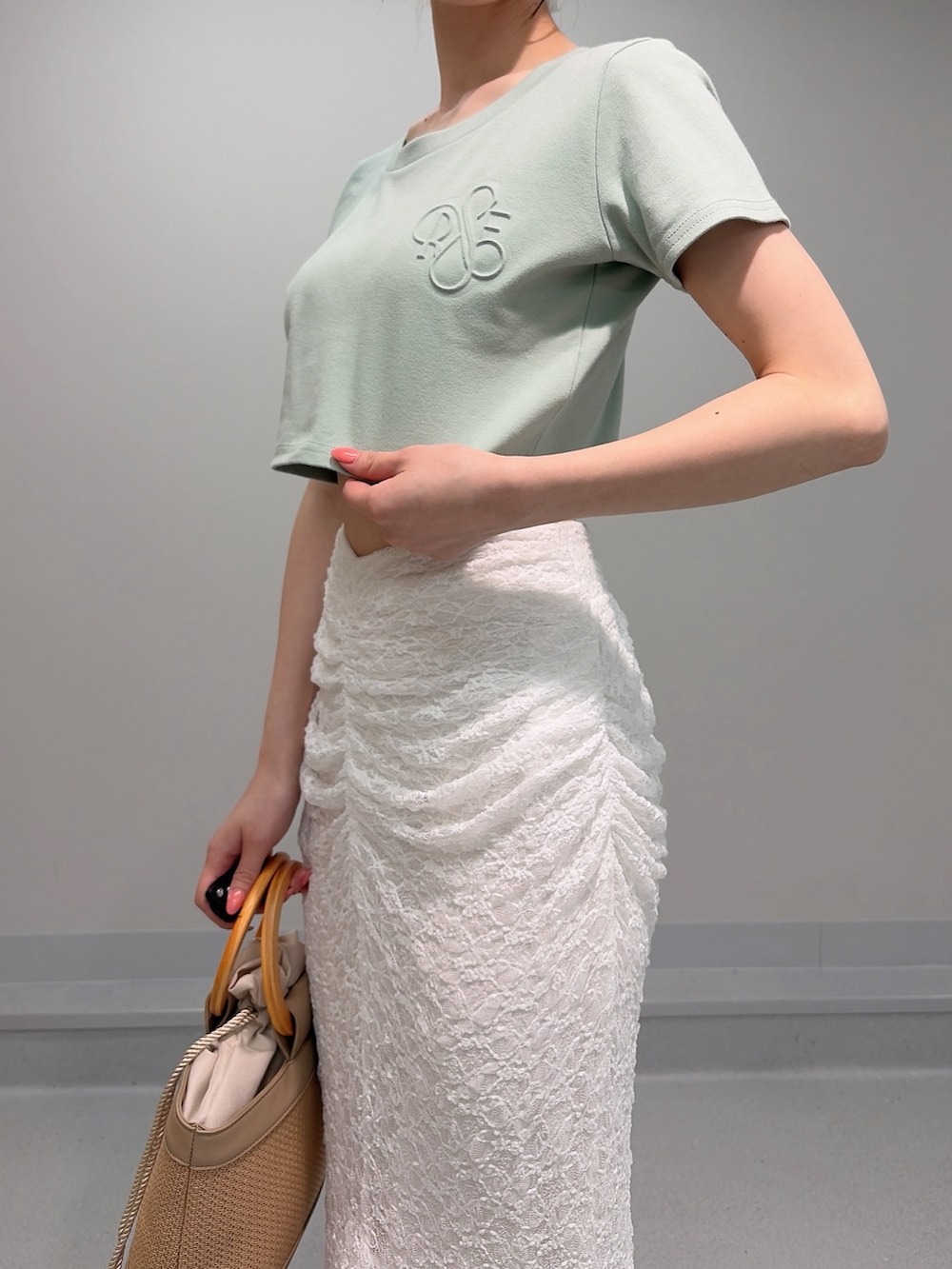ベージュ系のハンドバッグ、ベージュ系のサンダル、グリーン系のTシャツ/カットソーを着用したレディースの夏コーディネートの6枚目の写真