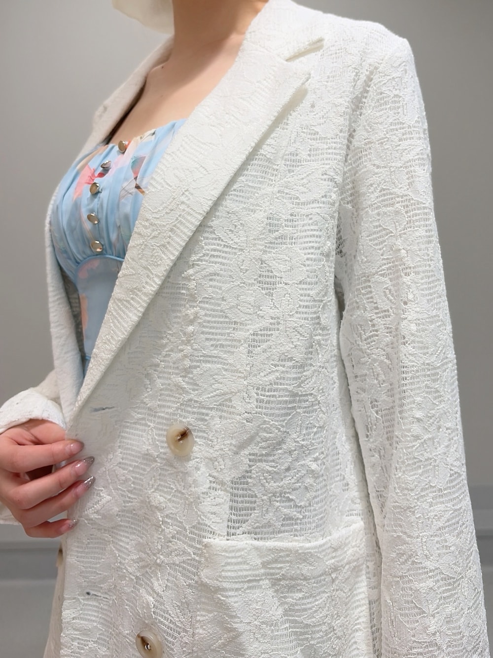 ホワイト系のテーラードジャケット、ブルー系のワンピース、ホワイト系のパンプスを着用したレディースの冬コーディネートの6枚目の写真