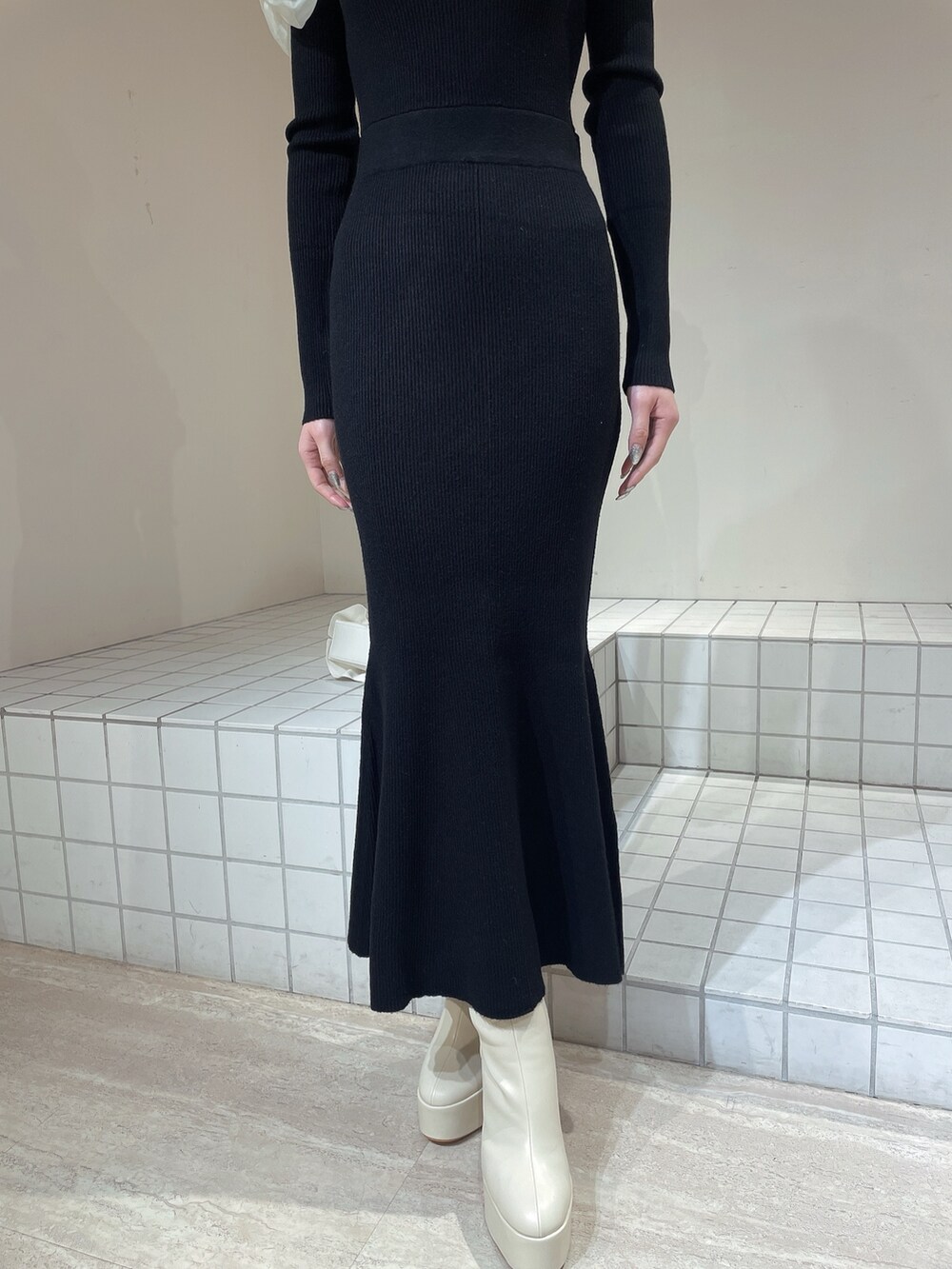 ホワイト系のハンドバッグ、ホワイト系のブーツ、ブラック系のワンピースを着用したレディースの冬コーディネートの7枚目の写真