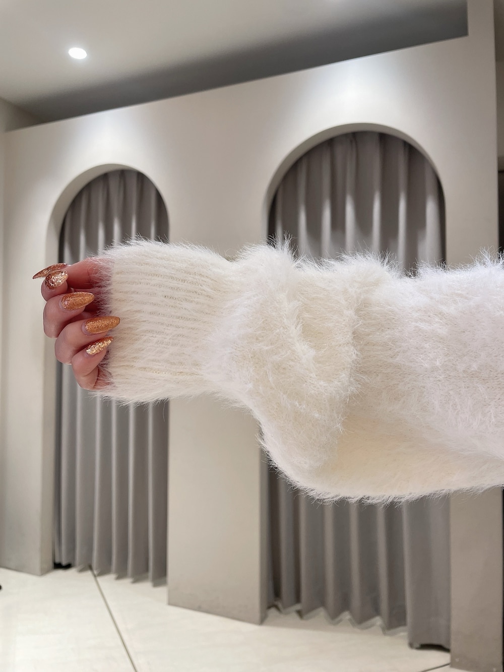 ホワイト系のニット/セーター、ブルー系のデニムパンツ、ブラック系のブーツを着用したレディースの秋コーディネートの8枚目の写真