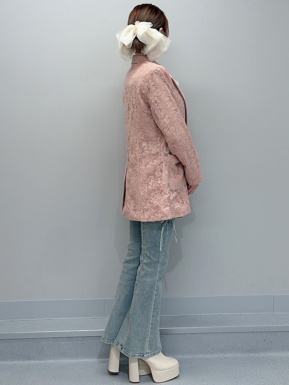 ピンク系のテーラードジャケット、ホワイト系のニット/セーター、ブルー系のデニムパンツを着用したレディースの冬コーディネートの2枚目の写真