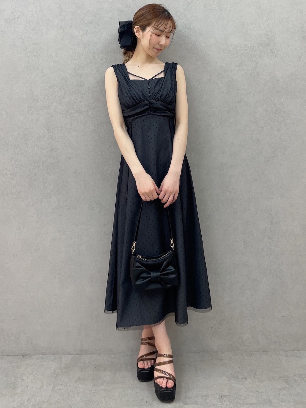 ブラック系のサンダル、ブラック系のワンピース、ブラック系のハンドバッグを着用したレディースの春コーディネートの2枚目の写真