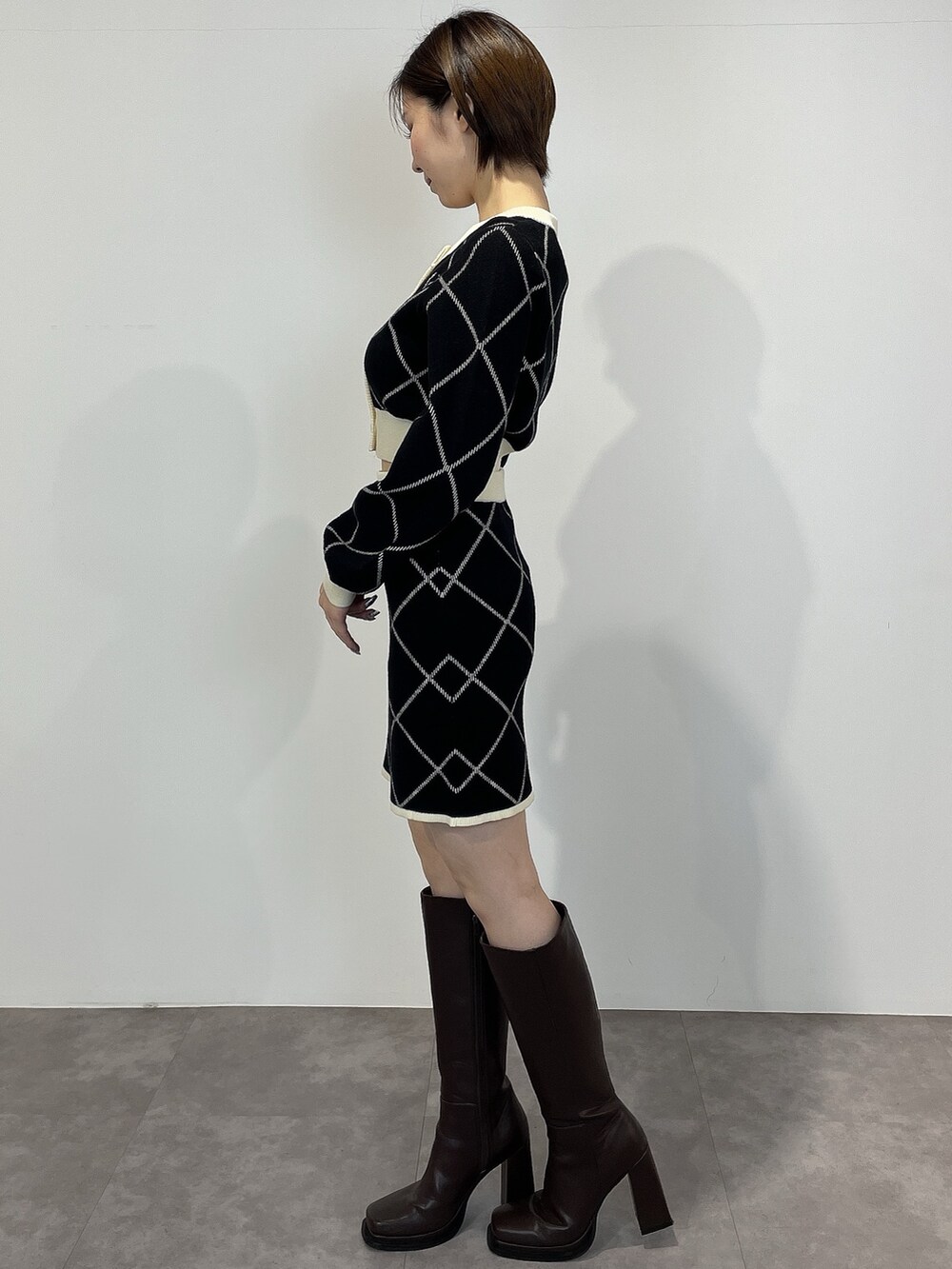 ブラック系のカーディガン/ボレロ、ブラック系のスカート、ブラウン系のブーツを着用したレディースの冬コーディネートの3枚目の写真