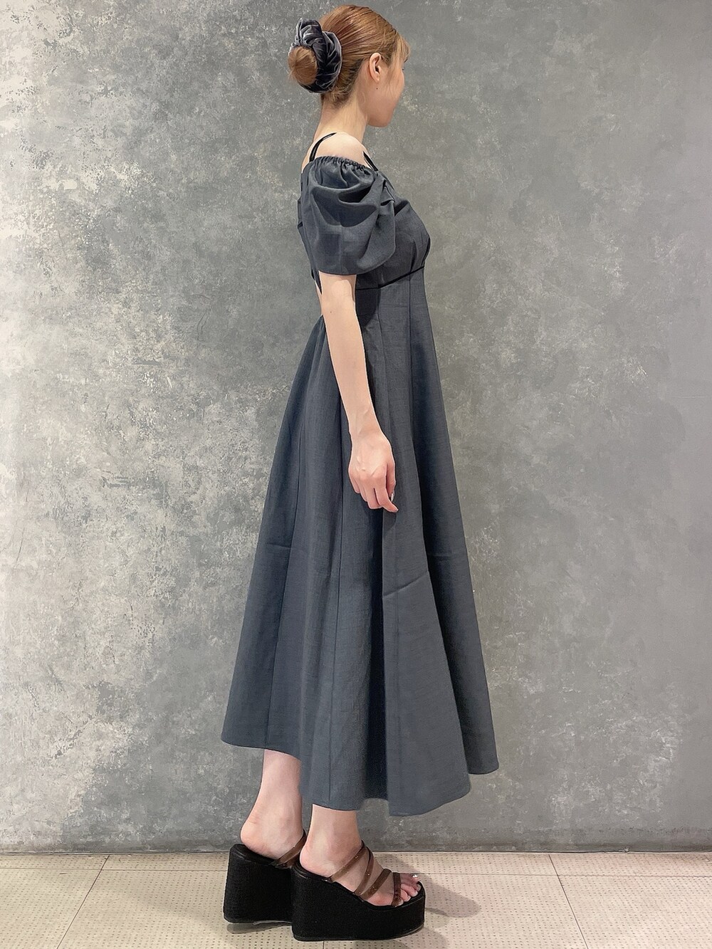 グレー系のワンピース、ブラック系のサンダル、グレー系のシュシュを着用したレディースの夏コーディネートの2枚目の写真