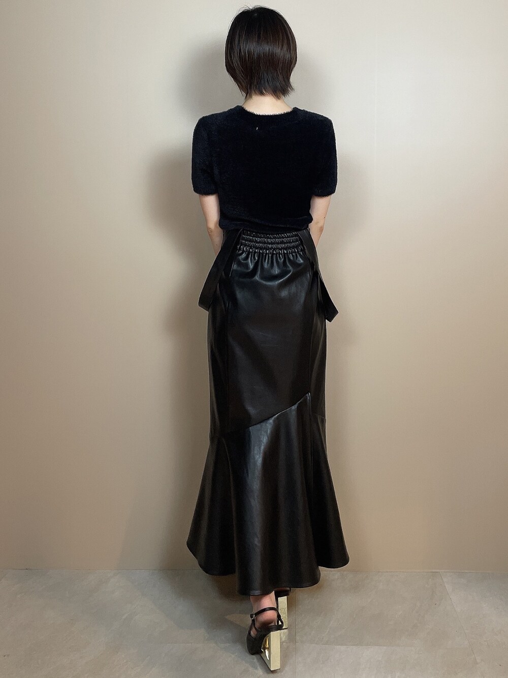 ブラック系のニット/セーター、ブラック系のスカート、ブラック系のサンダルを着用したレディースの夏コーディネートの4枚目の写真