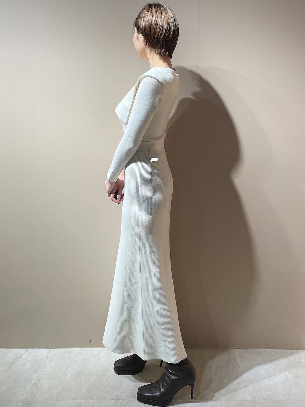 ホワイト系のダウンジャケット/コート、ホワイト系のワンピース、ブラウン系のブーツを着用したレディースの秋コーディネートの7枚目の写真