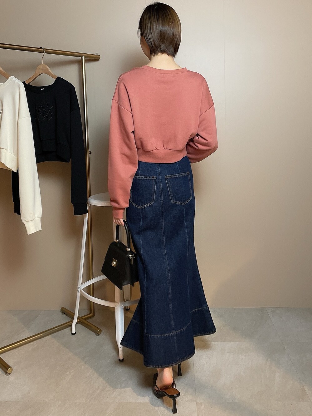 ブラック系のハンドバッグ、オレンジ系のスウェット、ブルー系のデニムスカートを着用したレディースの冬コーディネートの3枚目の写真