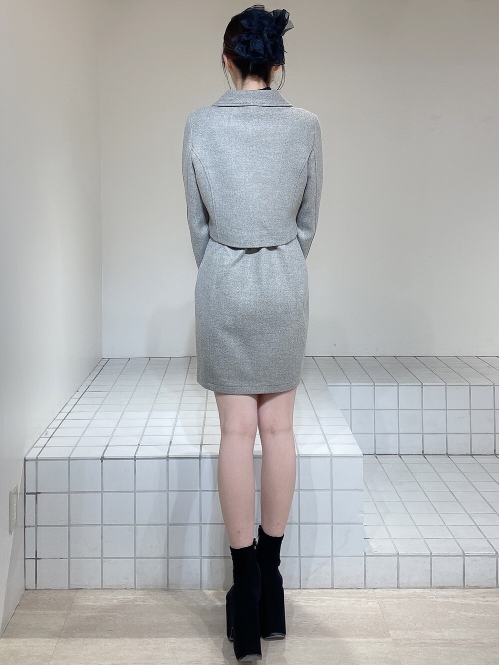 グレー系のその他アウター、グレー系のジャンパースカート、ブラック系のニット/セーターを着用したレディースの冬コーディネートの4枚目の写真