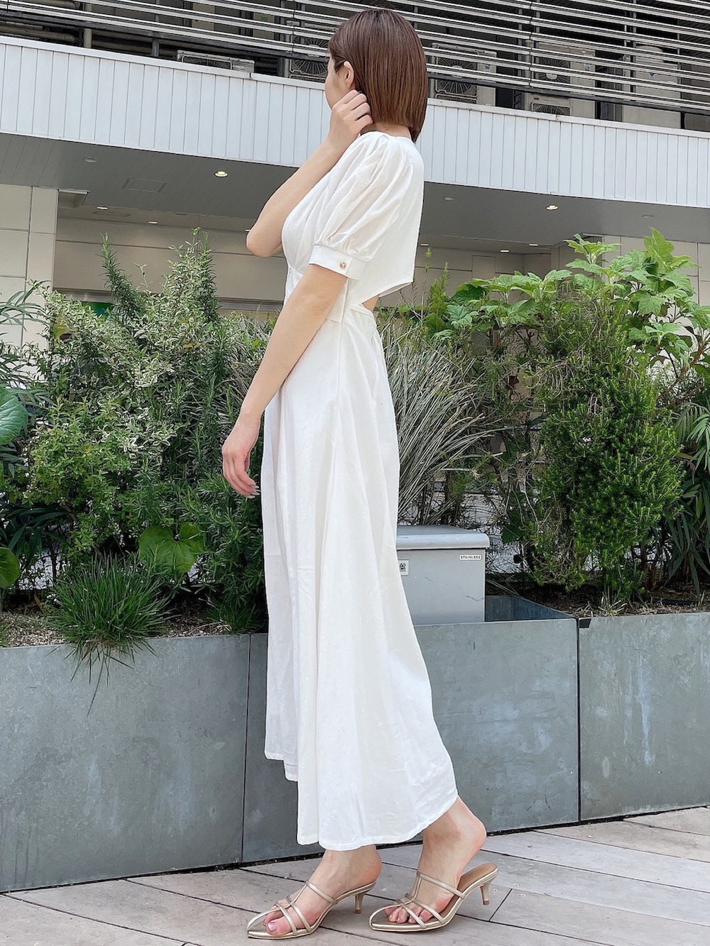 ホワイト系のワンピース、ブルー系のデニムジャケット、ゴールド系のサンダルを着用したレディースの春コーディネートの4枚目の写真