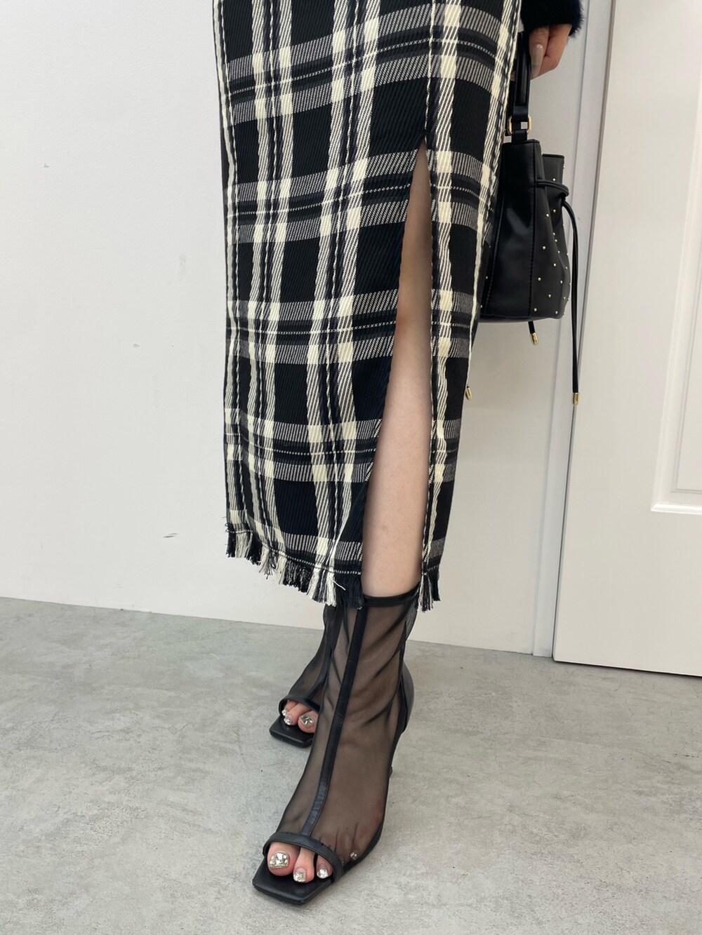 ブラック系のニット/セーター、ブラック系のスカート、ブラック系のハンドバッグを着用したレディースの夏コーディネートの8枚目の写真