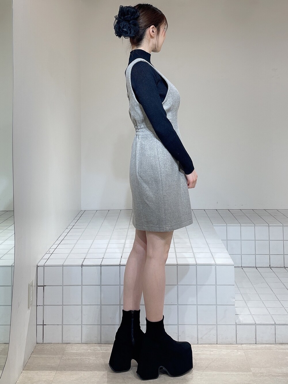 グレー系のその他アウター、グレー系のジャンパースカート、ブラック系のニット/セーターを着用したレディースの冬コーディネートの6枚目の写真