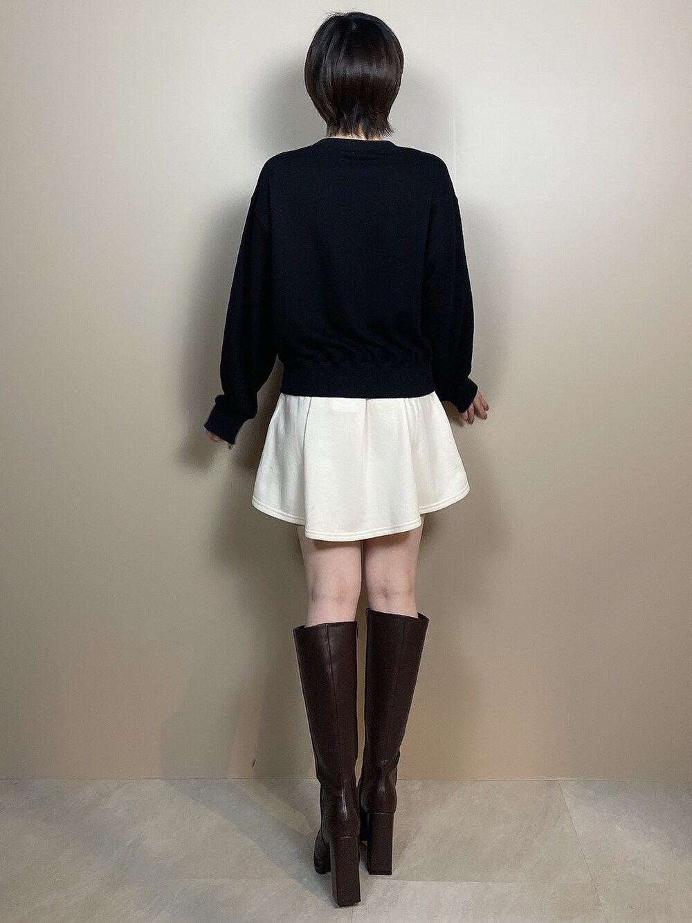 ホワイト系のスカート、ブラウン系のブーツ、ブラック系のスウェットを着用したレディースの夏コーディネートの4枚目の写真