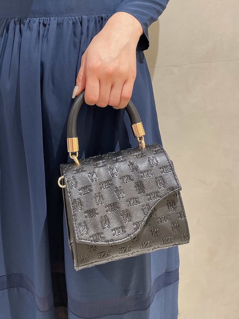 ブラック系のハンドバッグ、ブルー系のワンピース、ブラック系のパンプスを着用したレディースの冬コーディネートの6枚目の写真