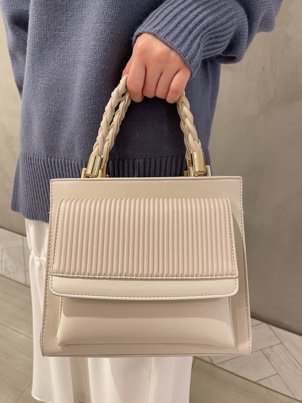 ホワイト系のブーツ、ホワイト系のハンドバッグ、ブルー系のニット/セーターを着用したレディースの冬コーディネートの7枚目の写真