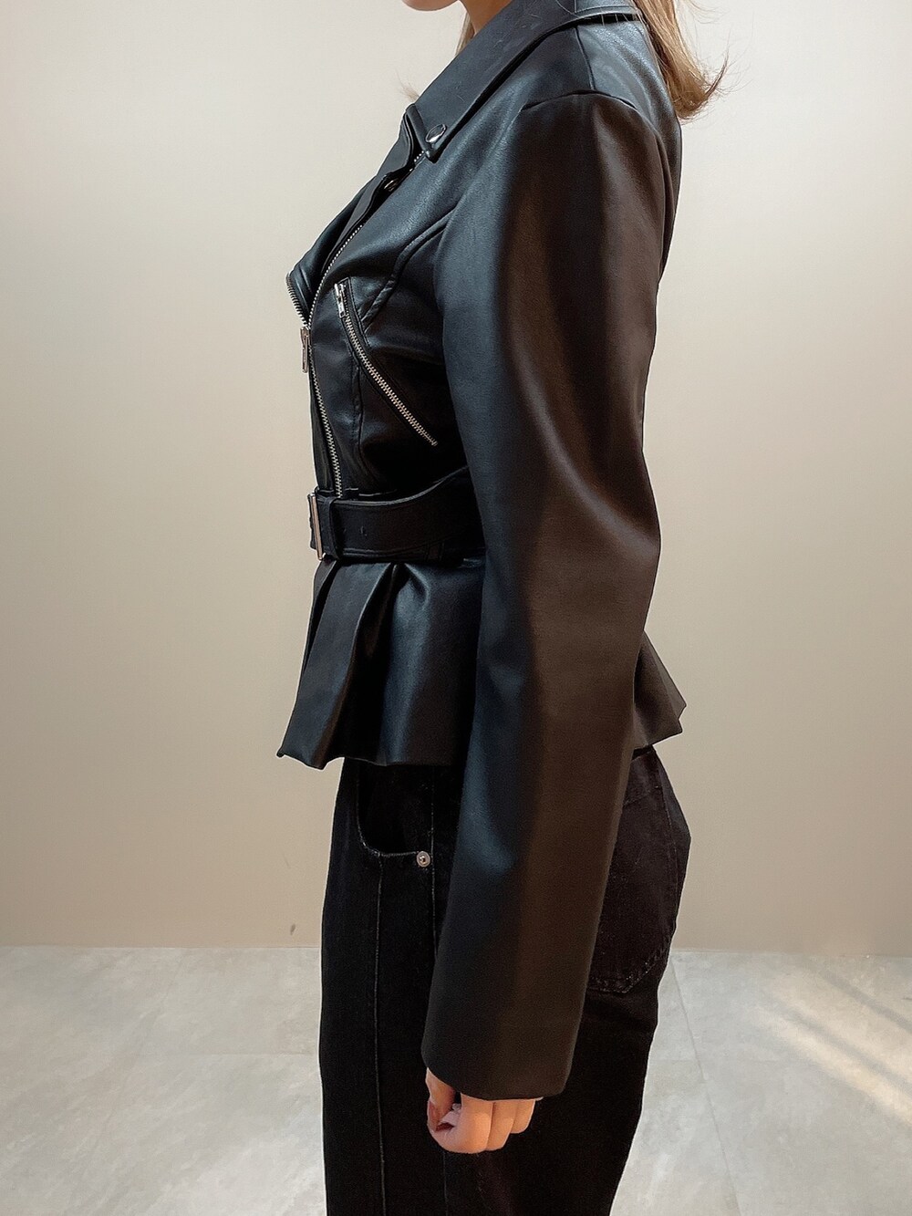 ブラック系のライダースジャケット、ブラック系のデニムパンツ、ブラック系のパンプスを着用したレディースの冬コーディネートの6枚目の写真