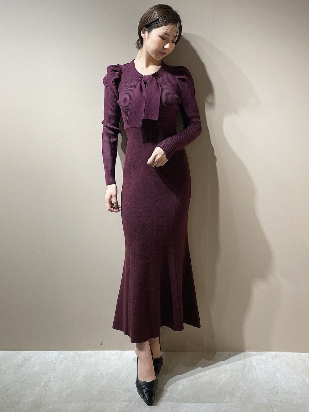 レッド系のワンピース、ブラック系のパンプスを着用したレディースの秋コーディネートの2枚目の写真