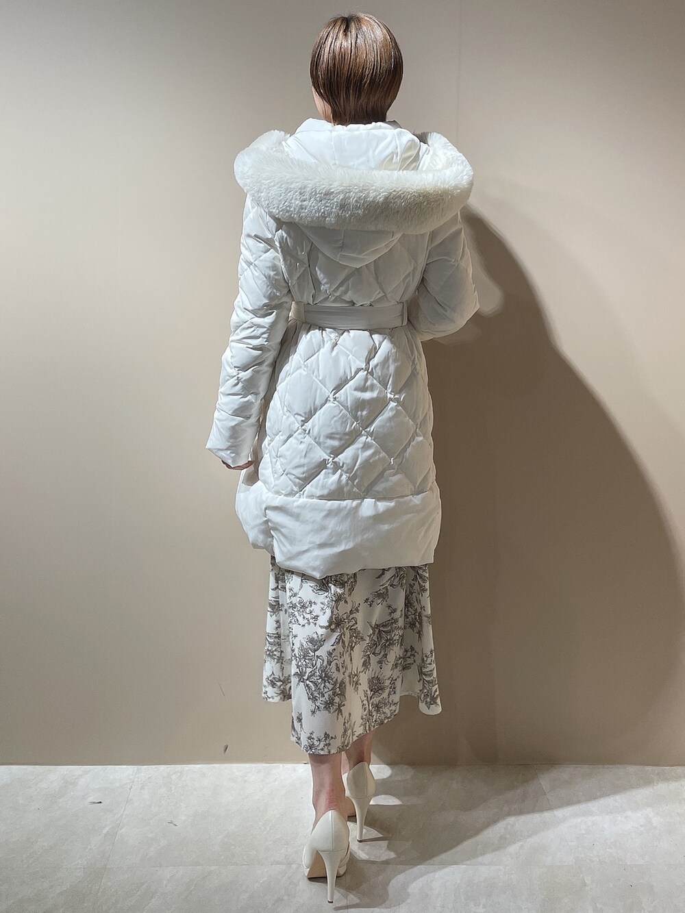 ホワイト系のダウンジャケット/コート、ホワイト系のパンプス、ベージュ系のワンピースを着用したレディースの秋コーディネートの4枚目の写真
