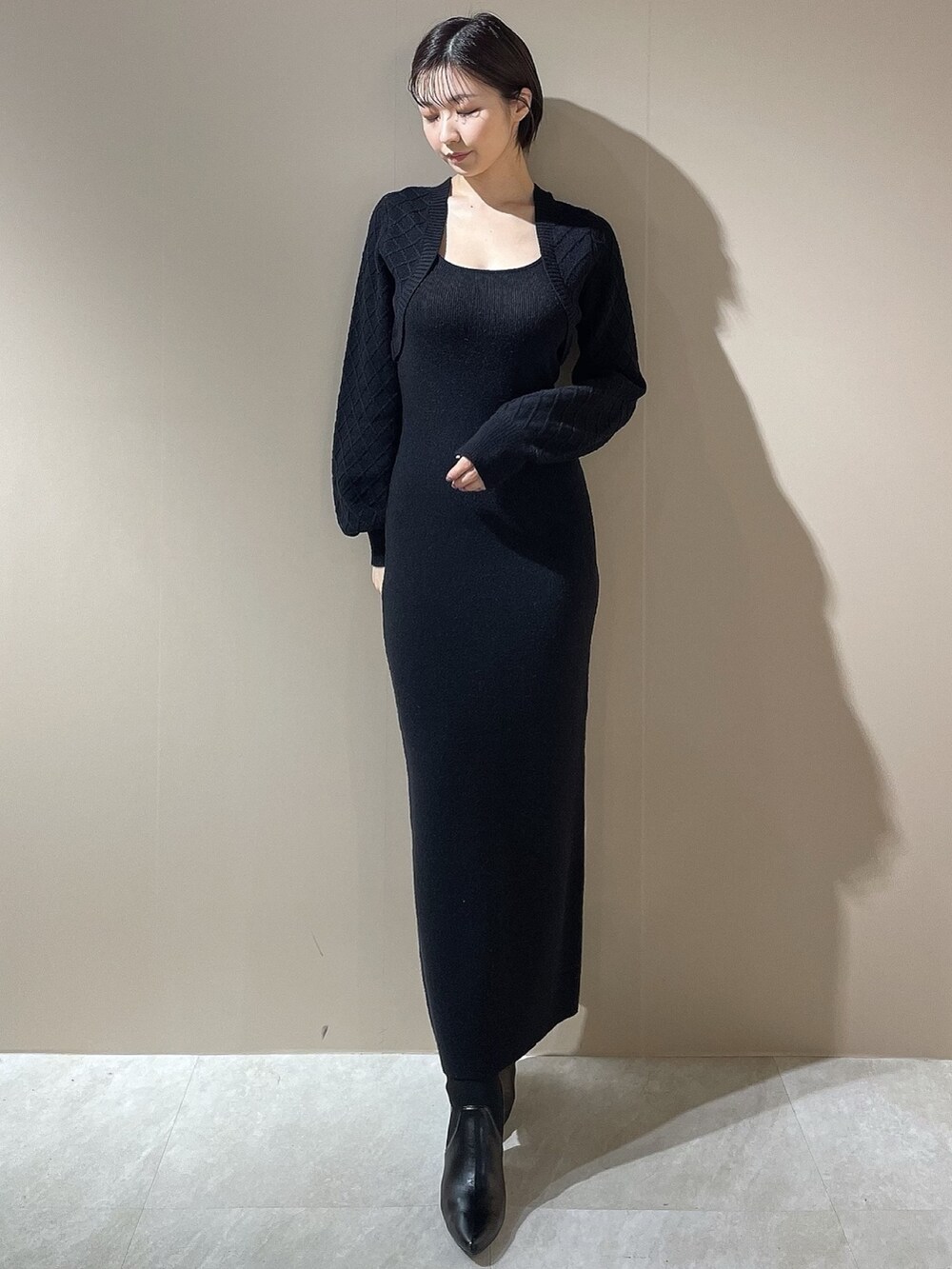 ブラック系のダウンジャケット/コート、ブラック系のワンピース、ブラック系のブーツを着用したレディースの秋コーディネートの5枚目の写真