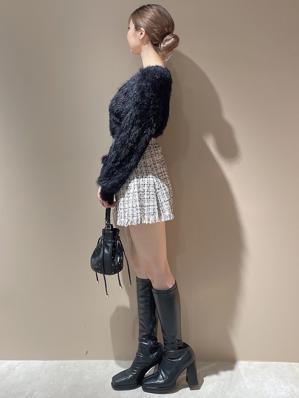 ブラック系のハンドバッグ、ブラック系のカーディガン/ボレロ、ホワイト系のスカートを着用したレディースの秋コーディネートの3枚目の写真