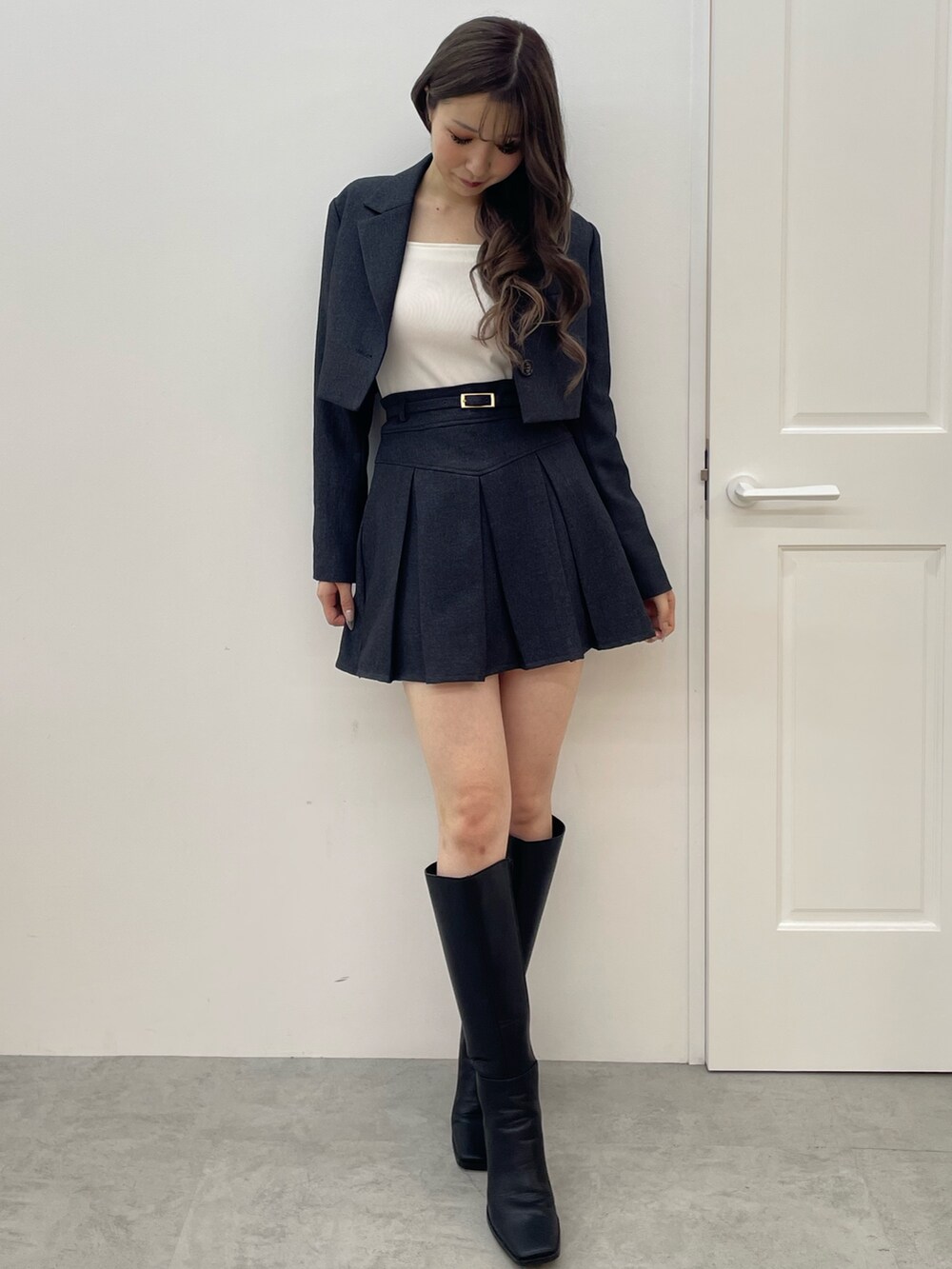 グレー系のテーラードジャケット、グレー系のスカート、ブラック系のブーツを着用したレディースの夏コーディネートの2枚目の写真