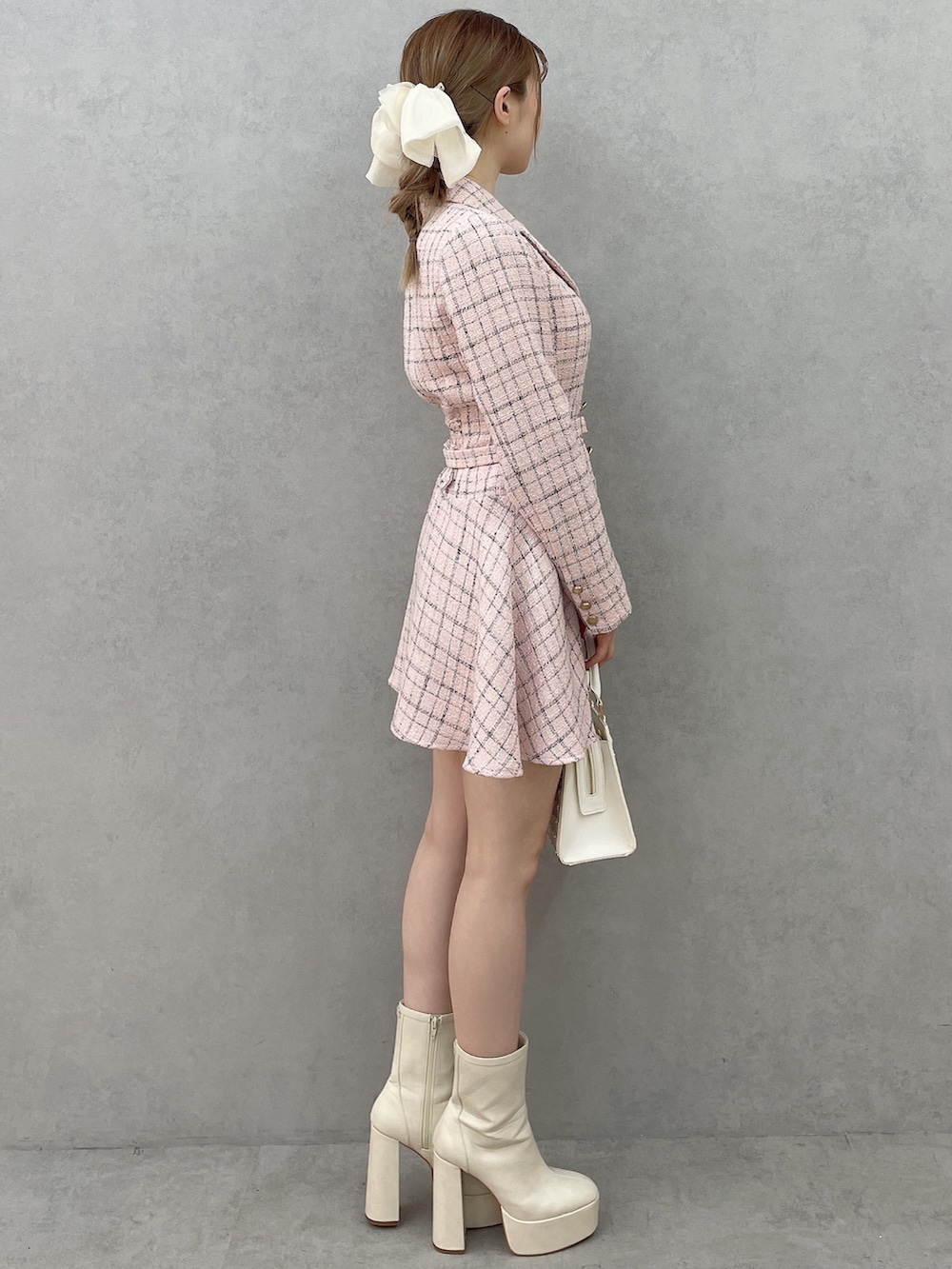 ピンク系のワンピース、ホワイト系のハンドバッグ、ホワイト系のブーツを着用したレディースの春コーディネートの3枚目の写真