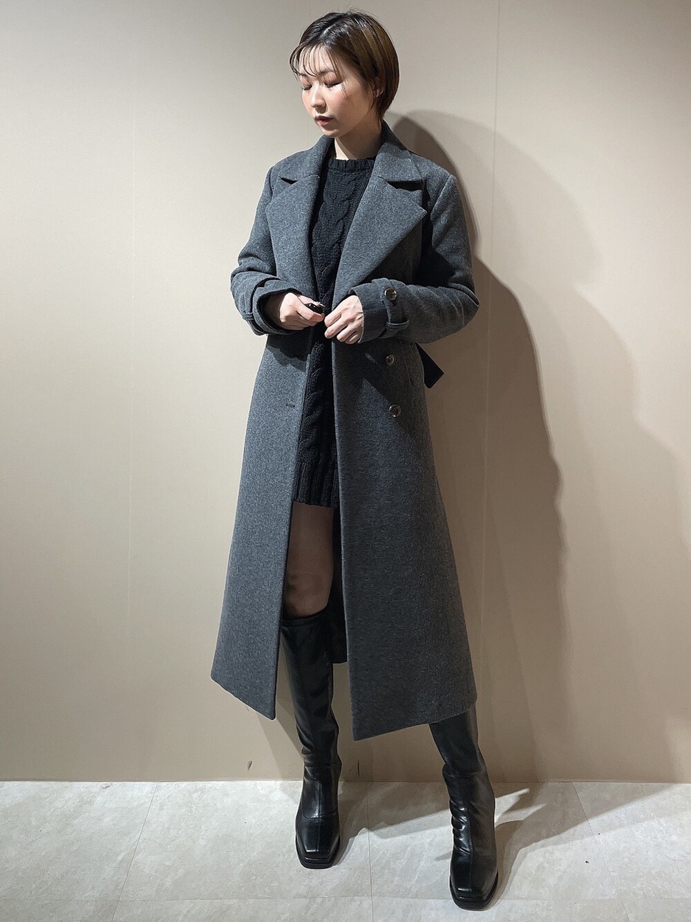 ブラック系のニット/セーター、グレー系のチェスターコート、ブラック系のブーツを着用したレディースの秋コーディネートの2枚目の写真