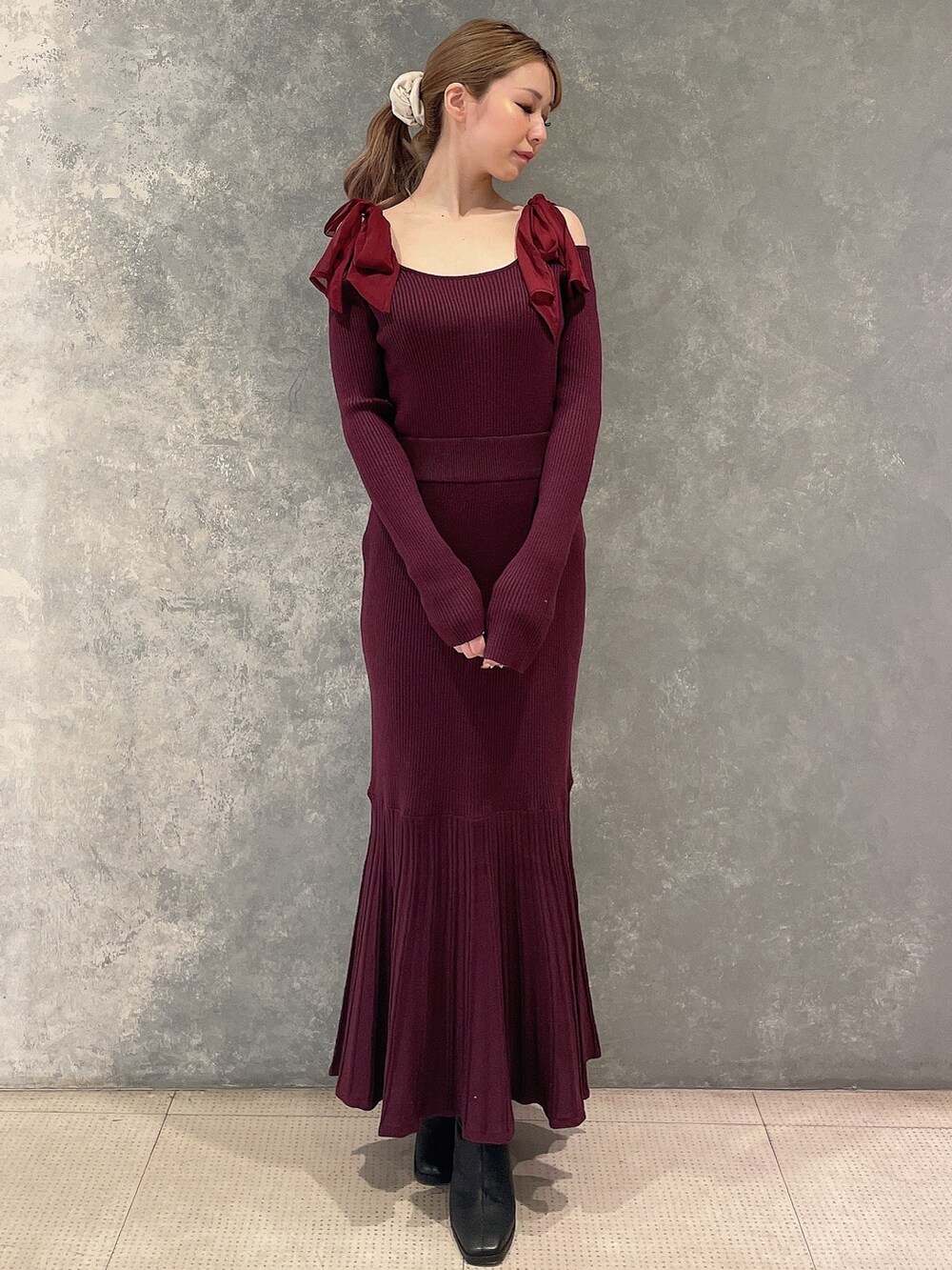 レッド系のワンピース、ブラック系のブーツを着用したレディースの秋コーディネートの2枚目の写真