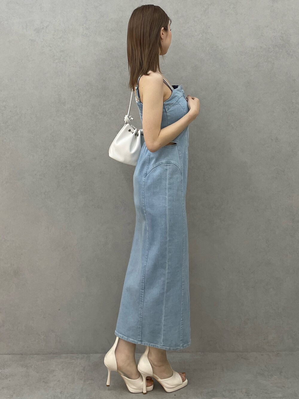 ブルー系のデニムジャケット、ブルー系のワンピース、ホワイト系のハンドバッグを着用したレディースの春コーディネートの5枚目の写真