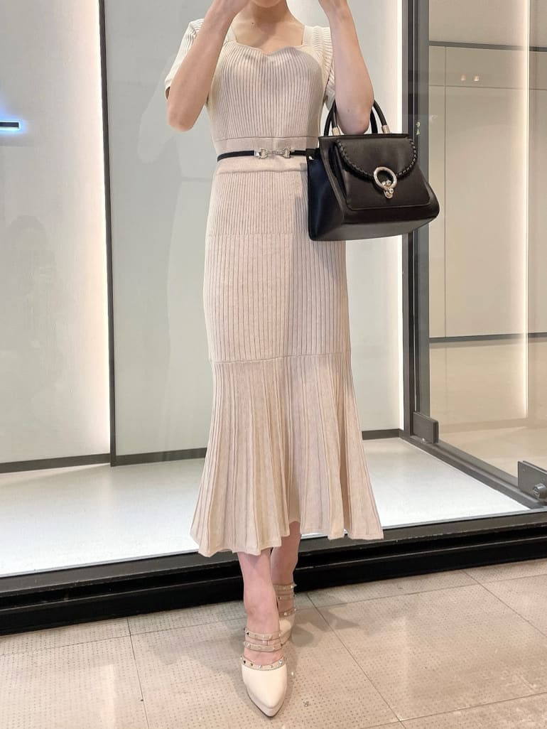 ブラック系のハンドバッグ、ベージュ系のワンピース、ベージュ系のパンプスを着用したレディースの秋コーディネートの2枚目の写真