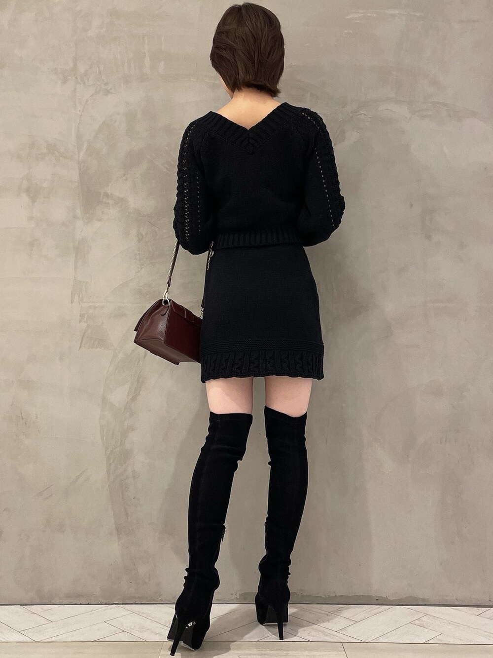 ブラウン系のハンドバッグ、ブラック系のブーツ、ブラック系のニット/セーターを着用したレディースの秋コーディネートの4枚目の写真