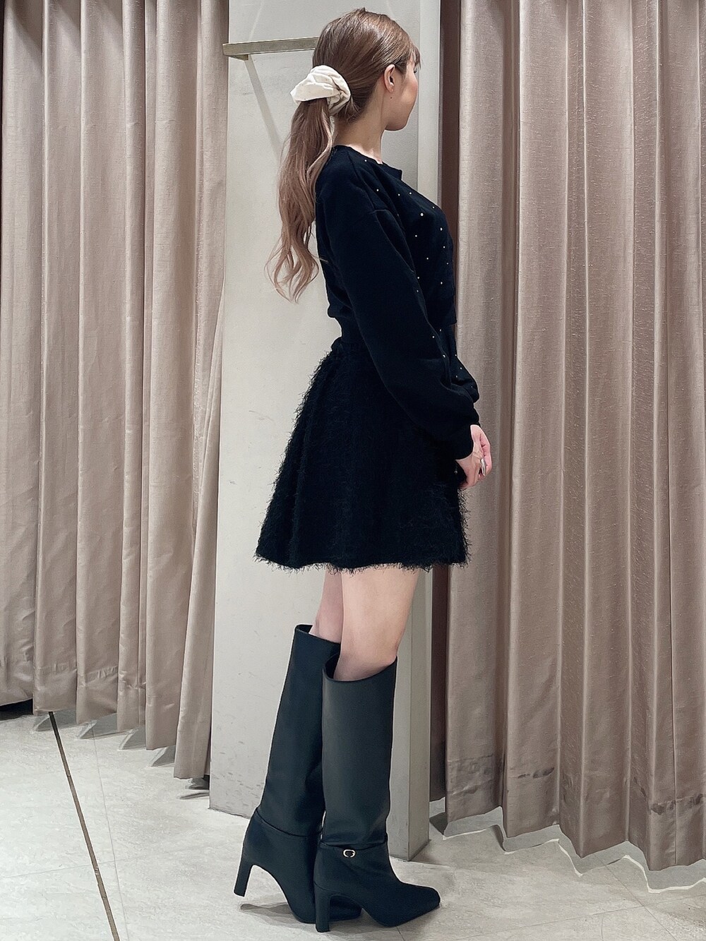 ブラック系のスウェット、ブラック系のスカート、ブラック系のブーツを着用したレディースの秋コーディネートの3枚目の写真