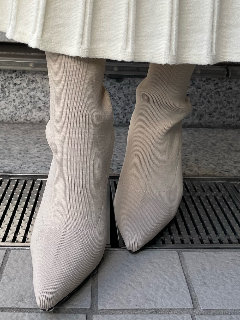 ベージュ系のトレンチコート、ブラウン系のワンピース、ホワイト系のブーツを着用したレディースの冬コーディネートの9枚目の写真