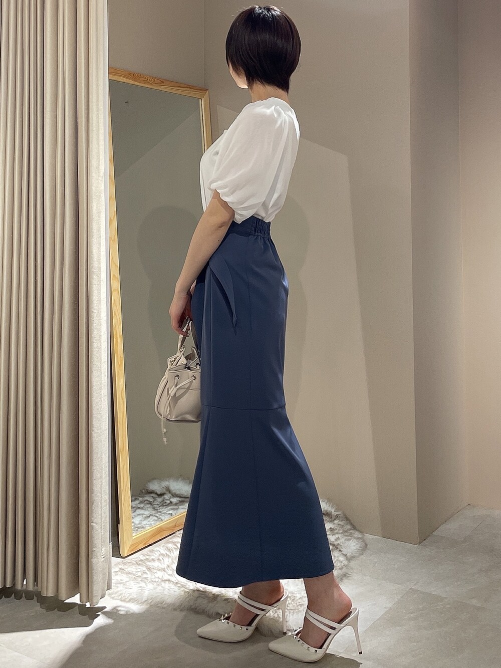 ホワイト系のハンドバッグ、ホワイト系のパンプス、ブルー系のスカートを着用したレディースの春コーディネートの3枚目の写真