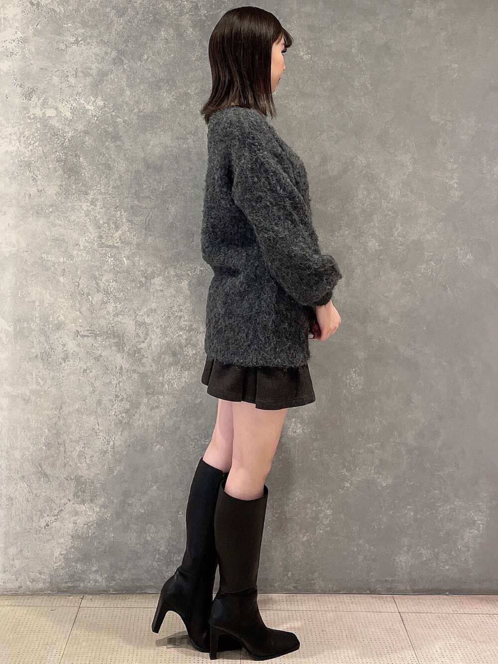 グレー系のワンピース、グレー系のスカート、ブラック系のブーツを着用したレディースの秋コーディネートの5枚目の写真