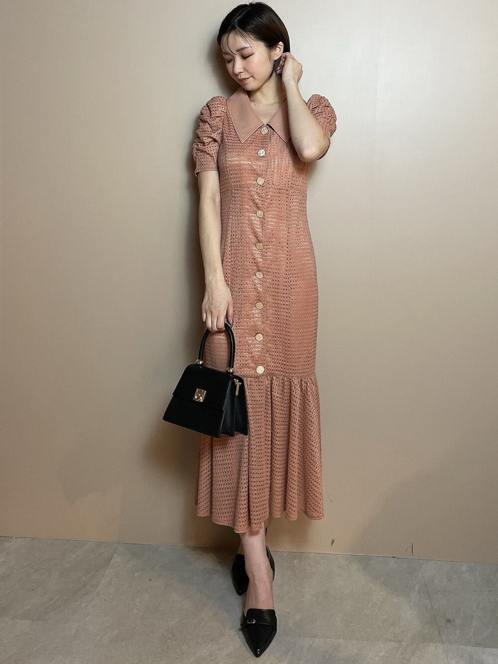 オレンジ系のワンピース、ブラック系のハンドバッグ、ブラック系のパンプスを着用したレディースの冬コーディネートの2枚目の写真