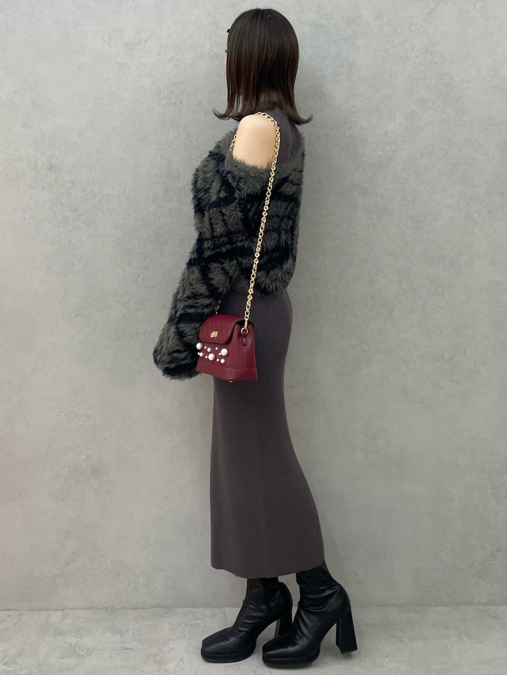 グレー系のワンピース、レッド系のショルダーバッグ、ブラック系のブーツを着用したレディースの秋コーディネートの3枚目の写真