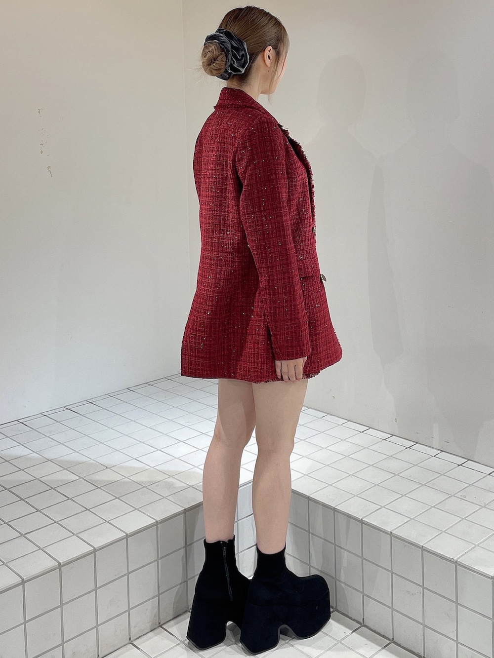 レッド系のテーラードジャケット、レッド系のスカート、ブラック系のニット/セーターを着用したレディースの秋コーディネートの3枚目の写真