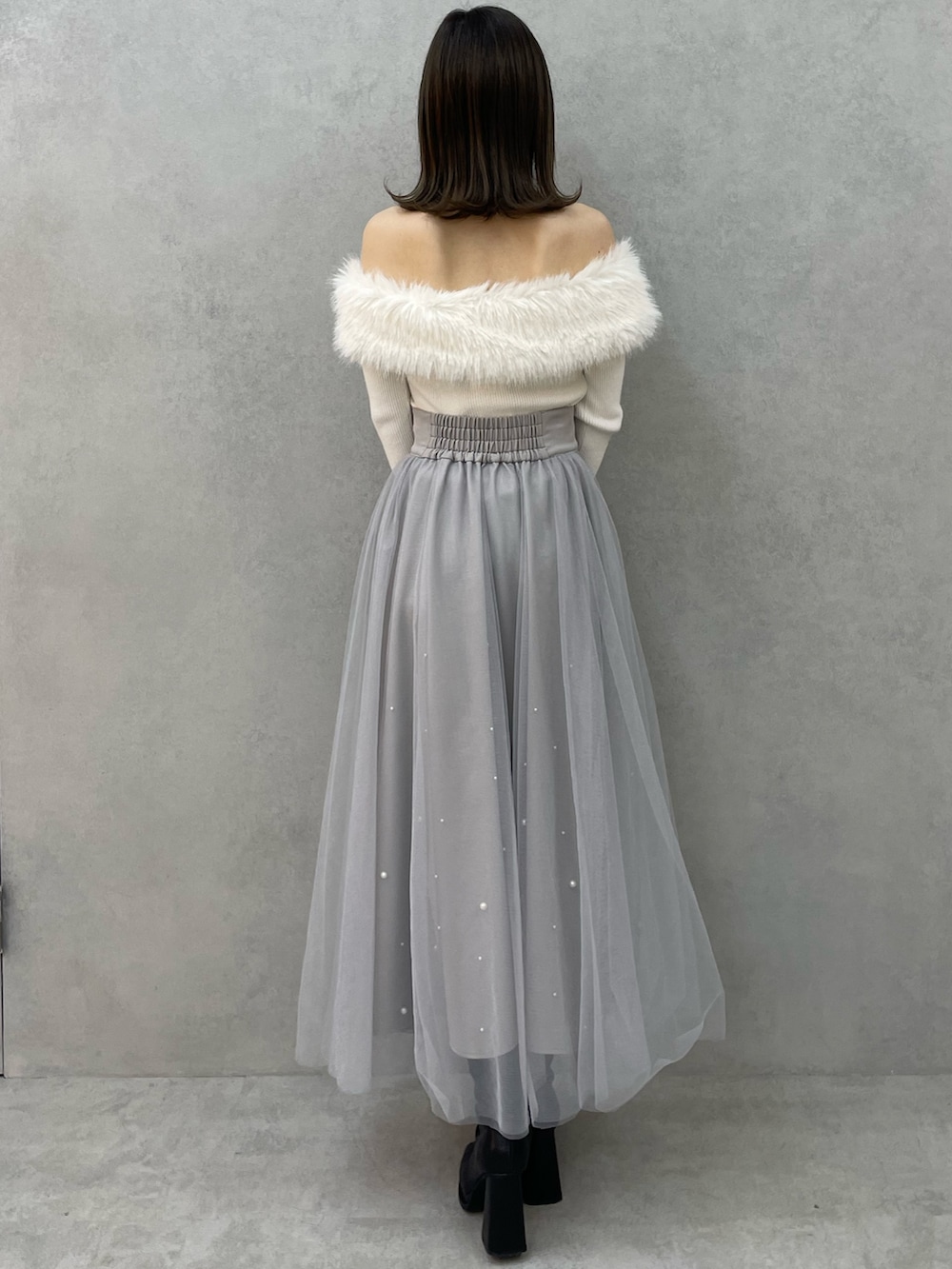 ホワイト系のニット/セーター、グレー系のスカート、ブラック系のブーツを着用したレディースの冬コーディネートの4枚目の写真