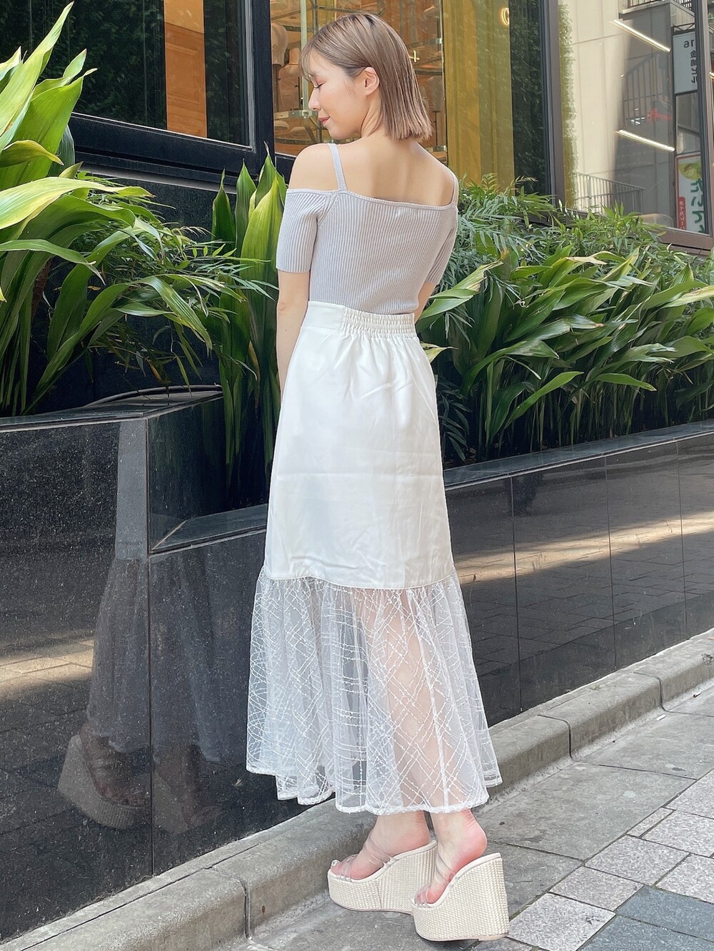 グレー系のニット/セーター、ホワイト系のスカート、ホワイト系のサンダルを着用したレディースの夏コーディネートの4枚目の写真