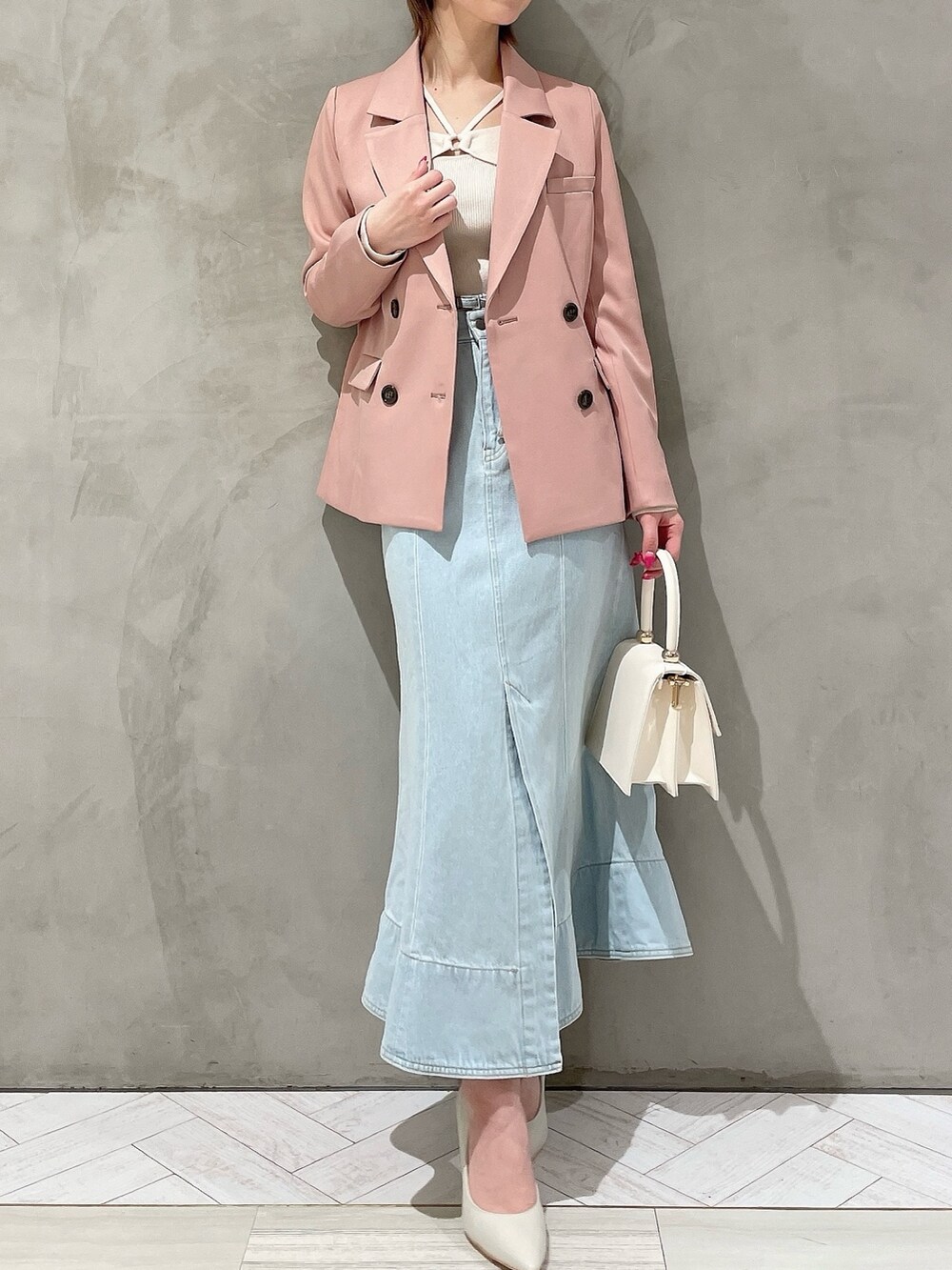 ホワイト系のハンドバッグ、ホワイト系のパンプス、ブルー系のデニムスカートを着用したレディースの冬コーディネートの3枚目の写真