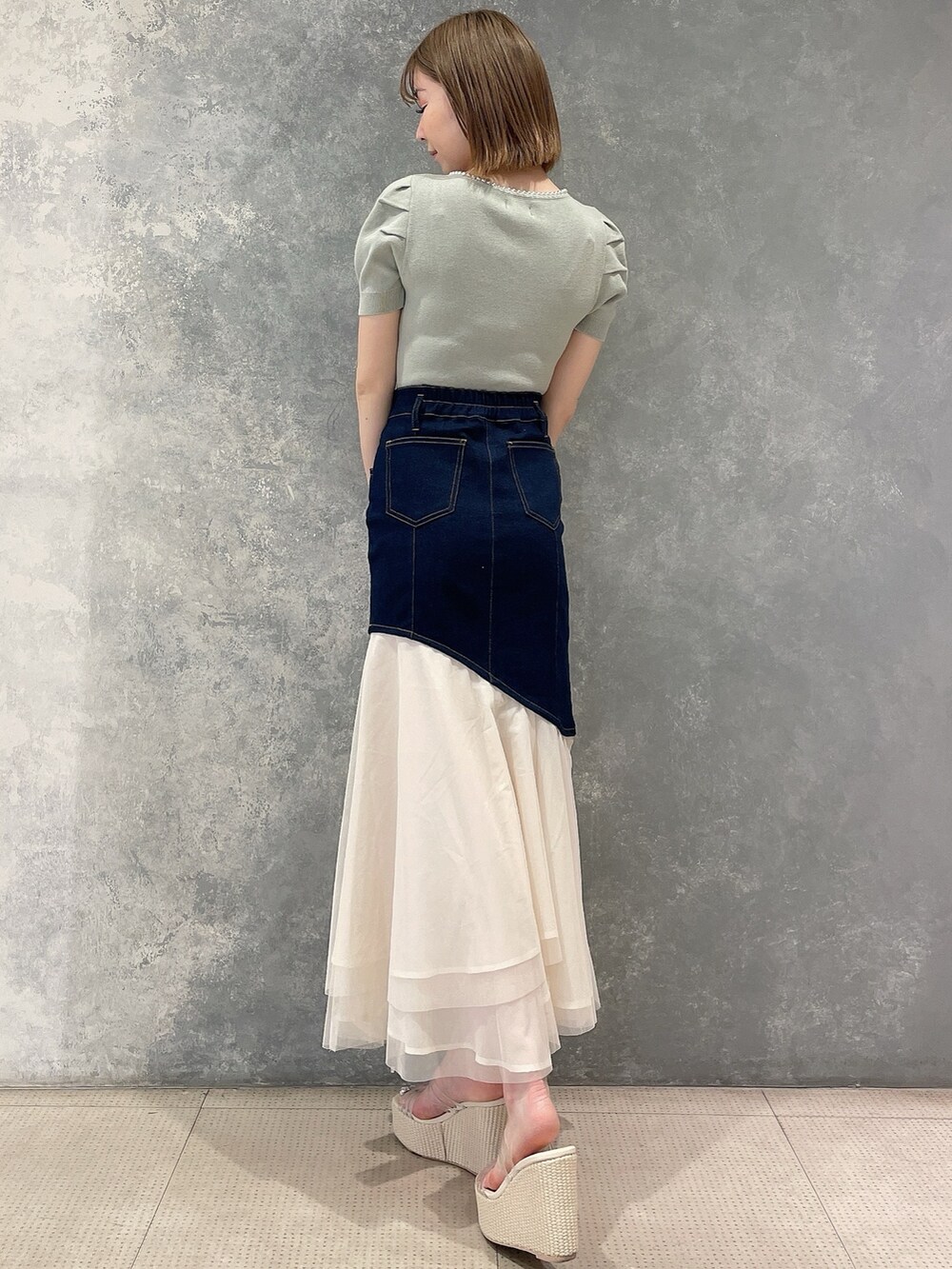 グリーン系のニット/セーター、ブルー系のスカート、ホワイト系のサンダルを着用したレディースの春コーディネートの3枚目の写真